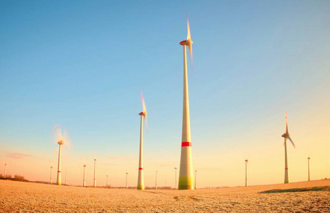 现代风力涡轮机生产能源在阳光明媚的春天的早晨。复古风格色调效果