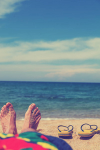 沙滩上的人在日光浴。脚和触发器的浅景深