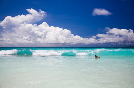热带海滩，男人享受绿松石海浪的海洋