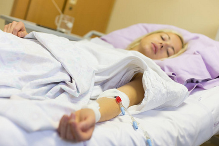 卧病在床的女病人，在医院照顾手术后恢复