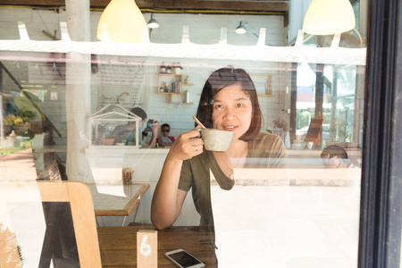 在咖啡馆里喝咖啡的年轻女性通过手机镜子