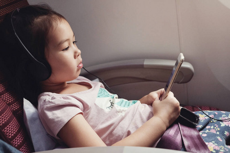 小亚洲女孩听音乐在飞行, 家庭出国旅行与孩子