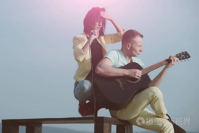 可爱女孩唱歌和英俊的男人,桌上弹吉他