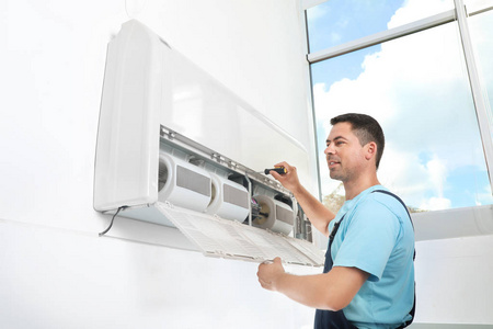 男技师在室内安装现代空调器
