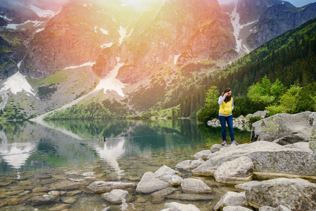 女人放松对湖和山的阳光景观