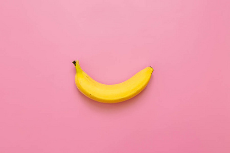 一只香蕉, 粉红色的背景。文本空间。简约理念