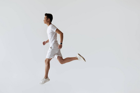 年轻亚洲慢跑运动员在灰色背景下的侧面观察