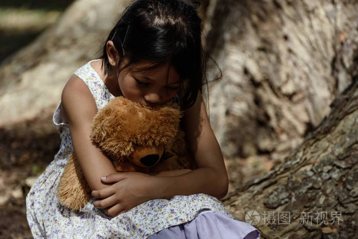 可爱的伤心的女孩在公园里的玩具熊,小女孩是你的拥抱