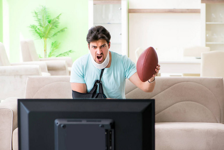 男子颈部和手臂受伤观看美国足球在电视上