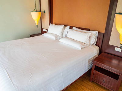 舒适的枕头在床上与灯装饰在旅馆卧室里