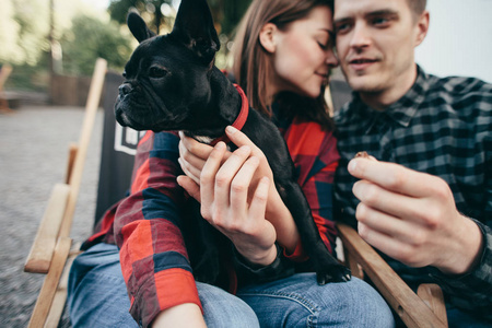 快乐的时髦夫妇与斗牛犬, 暑假。时尚的家庭与有趣的狗休息, 可爱的时刻