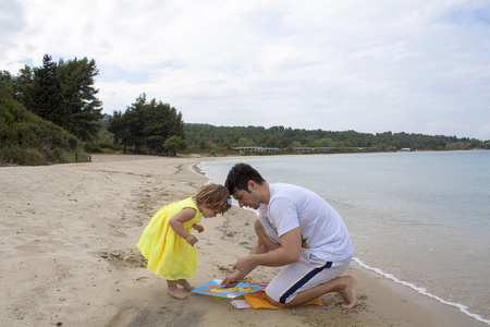 父亲和在海滩上的小女孩