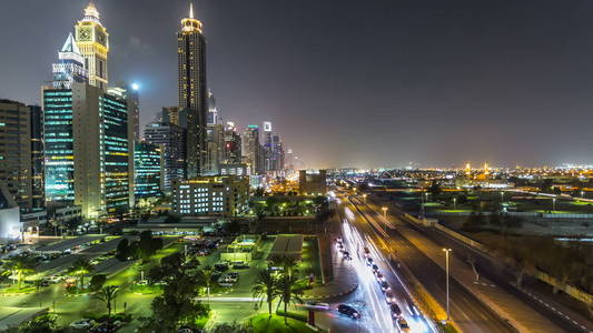 市中心的迪拜高塔夜游戏中时光倒流。摩天大楼的谢赫扎耶德路的鸟瞰图。在停车场和道路上的交通。闪烁的灯和创新