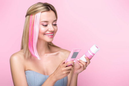 愉快的年轻妇女与五颜六色的头发线举行头发治疗被隔绝在粉红色