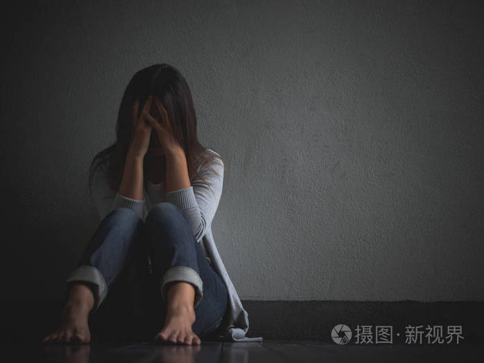 悲伤的女人抱着她的膝盖和哭泣.悲伤的女人独自坐在空