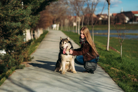 一个女孩在遛狗沿堤防。美丽的赫斯基狗。这条河。春天