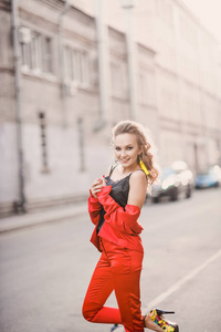 一个美丽明亮的女孩街道风格的肖像微笑着在一个阳光明媚的日子摆在红色西装