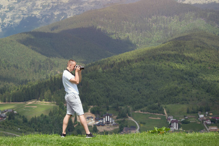 人与照相机站立在山和摄影自然。夏日