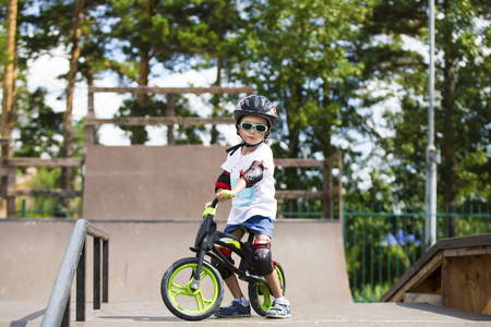 骑着太阳镜, 头盔和防护装备的自行车上的快乐男孩