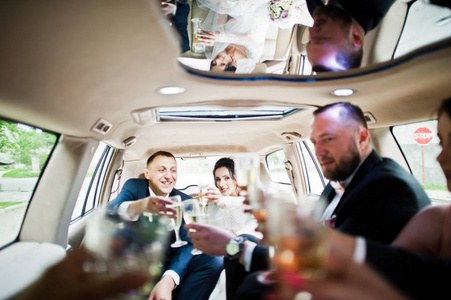 伴郎与伴娘和新婚夫妇在车里喝香槟