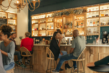 微笑着年轻的非洲裔美国人夫妇坐在柜台的酒吧交谈和喝, 而在一起约会
