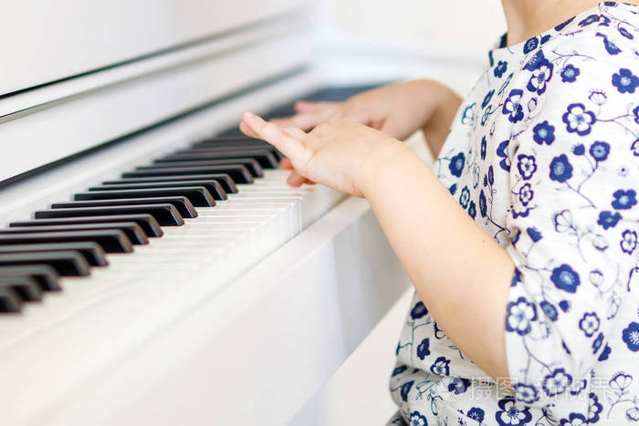 漂亮的小孩小女孩弹钢琴在客厅或音乐学校