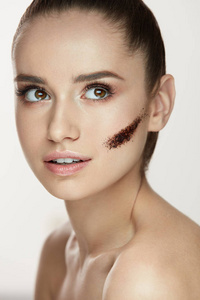 美容化妆品。条纹的咖啡面膜对皮肤的年轻女子