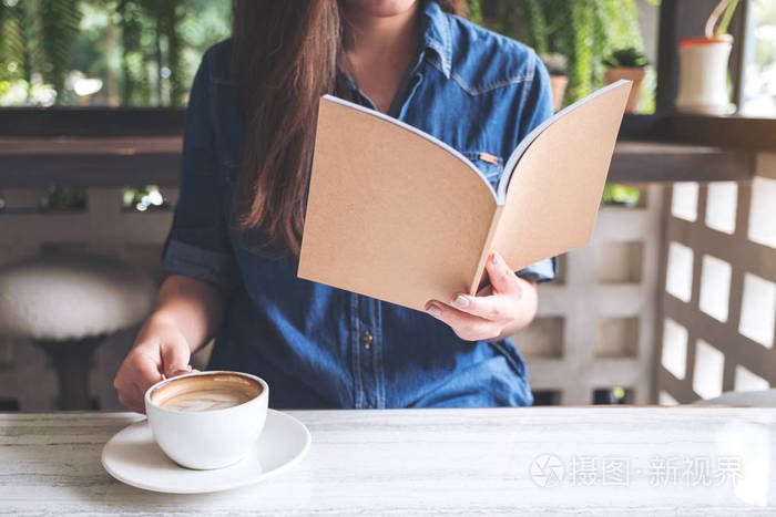 亚洲妇女在现代咖啡馆喝咖啡时看书的特写图像