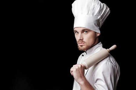 年轻胡子男人厨师在滚针在黑色背景上的白色统一举行
