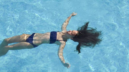 在水表面铺设泳池放松的年轻女子
