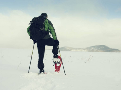 旅游检查雪鞋。与冬季夹克和大背包徒步旅行者在雪中散步