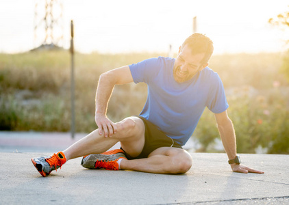 运动腿强健的运动员, 坐在沥青路上, 韧带损伤概念