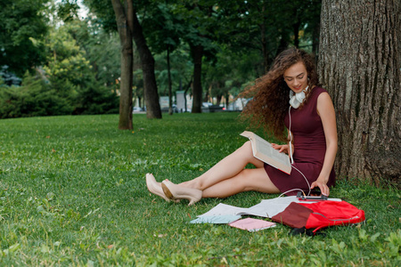 女学生藏品书并且坐树下
