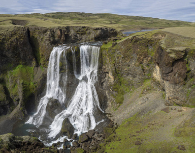 从南冰岛 Geirlandsa 河上美丽的 Fragifoss 瀑布看, 绿色的苔藓和岩石, 蓝天背景