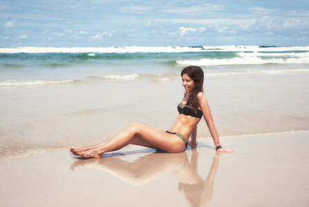 年轻漂亮的女人对成本海洋太阳浴