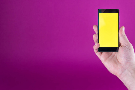 男性手特写与黄色屏幕智能手机在紫色背景