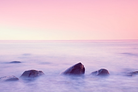 在海上的浪漫早晨。坚持从光滑水位的巨砾。与第一个炎热的太阳光线的粉红色 horozon