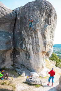 两名登山者被训练在一个大石头上。极限运动。在自然的康乐活动。一个女人克服了困难的攀登路线背景下的美丽的山谷