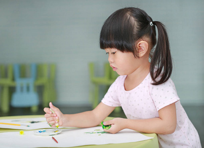可爱的亚洲儿童女孩用画笔和水的颜色绘画