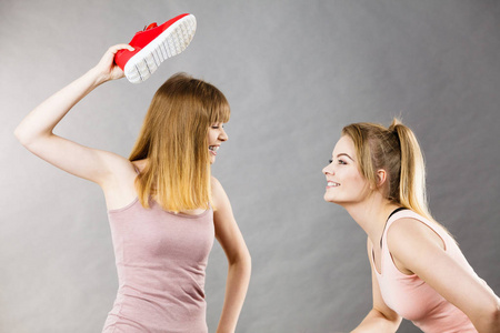 两个好斗的女人吵架, 用鞋子互相生气。女性争论概念
