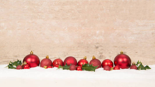 一行红色的圣诞彩球装饰在雪中