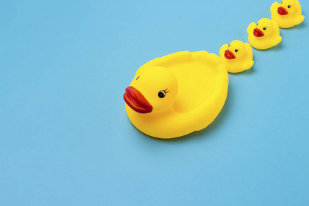 黄色的橡胶玩具, 妈妈鸭和小鸭子在蓝色的背景。妇幼保健和关爱儿童的概念, 儿童的教养和教育。平躺, 顶部视图