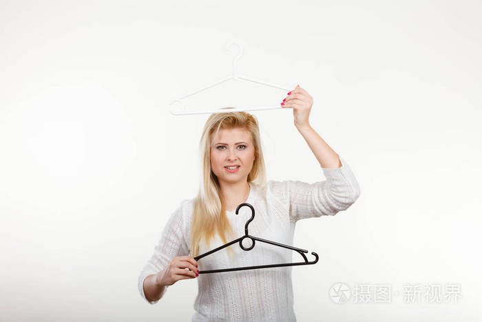 金发碧眼的幸福的女人,拿着衣架.工作室拍摄光背景