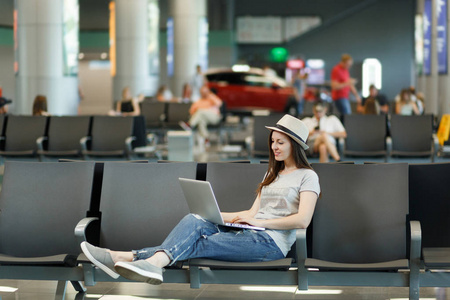 在国际机场大堂大厅等候的年轻平静的旅行者, 在笔记本电脑上工作。周末出游的旅客出国旅行。航空旅行, 飞行旅途概念