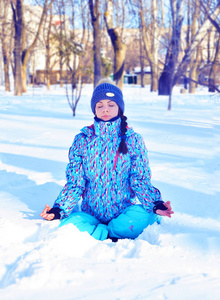 年轻的女孩坐在雪上和冥想