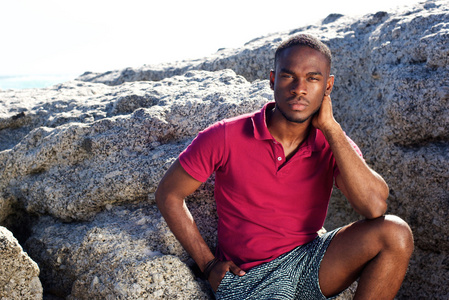 年轻的非洲男人坐在沙滩上