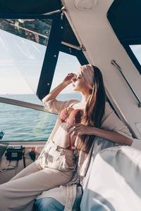 一个自信的有钱女人在海边的游艇上航行, 享受假期和温暖。