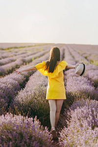 在夏季自然背景下, 紫色薰衣草花草场户外的年轻美女肖像。嫩的雌性靠近开花的灌木。生活方式概念