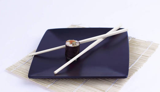 黑盘子上寿司和筷子的特写