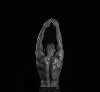 帅气肌肉后面的伸展手臂单色黑色和白色的年轻男性健身模型